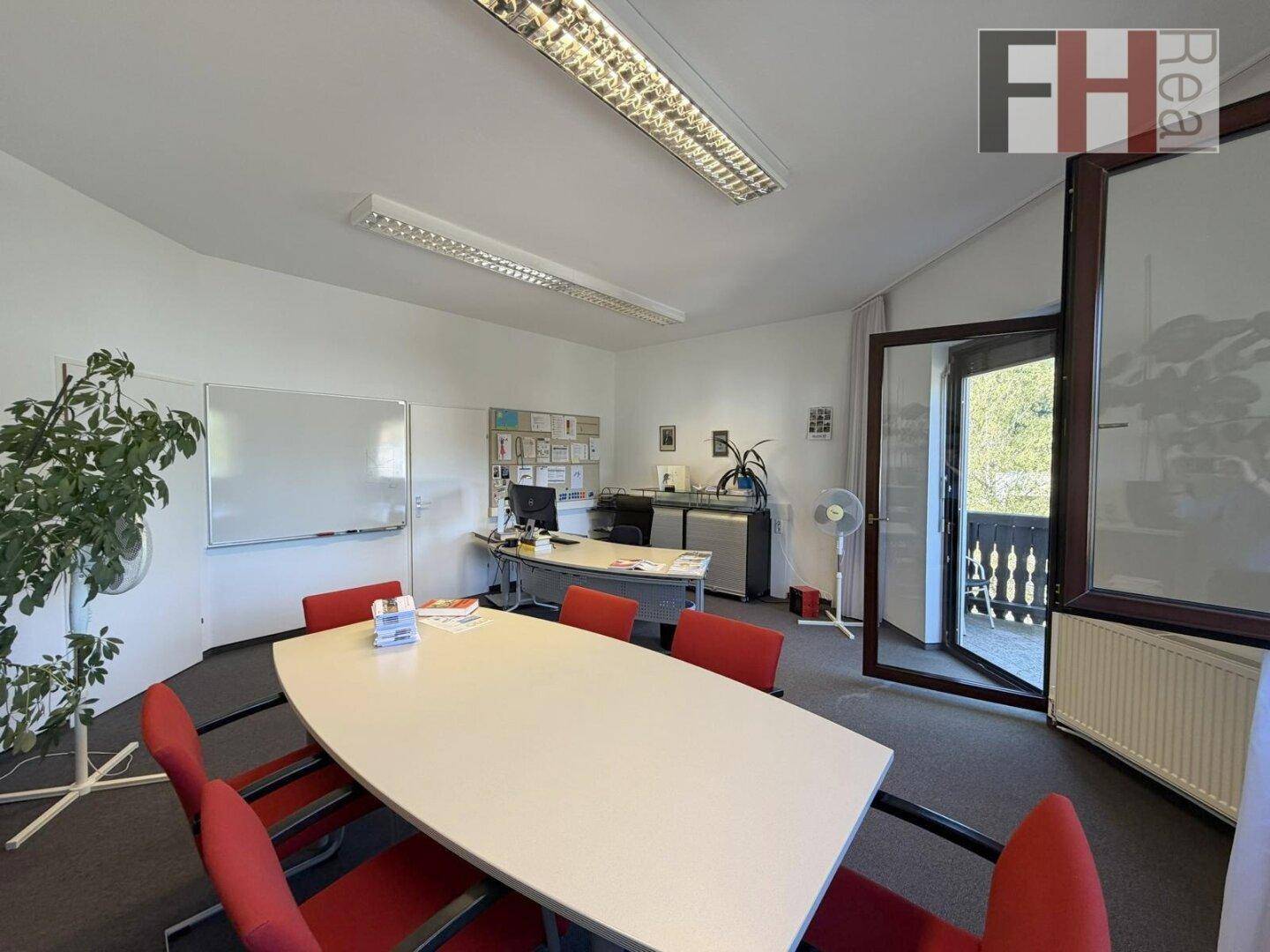 Geräumiges Büro mit Konferenztisch, Arbeitsplätzen und Zugang zu einem Balkon mit grüner Aussicht.