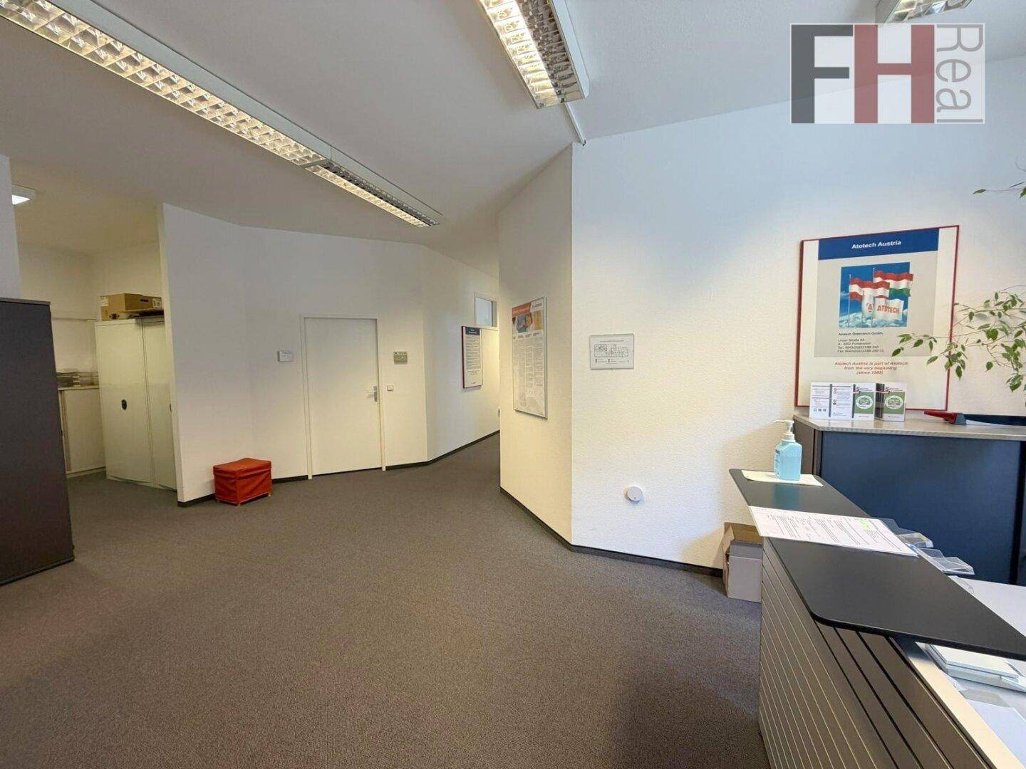 Empfangsbereich mit Theke und Flur, der zu weiteren Büroräumen führt.