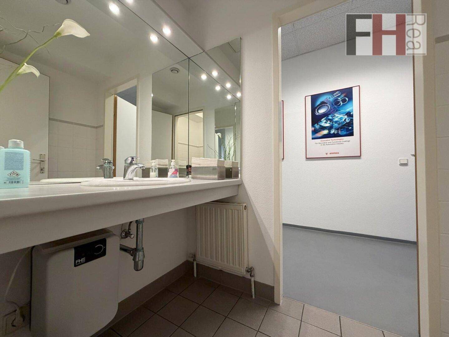 Badezimmer mit Waschbecken, großem Spiegel und Heizkörper unter dem Waschtisch.
