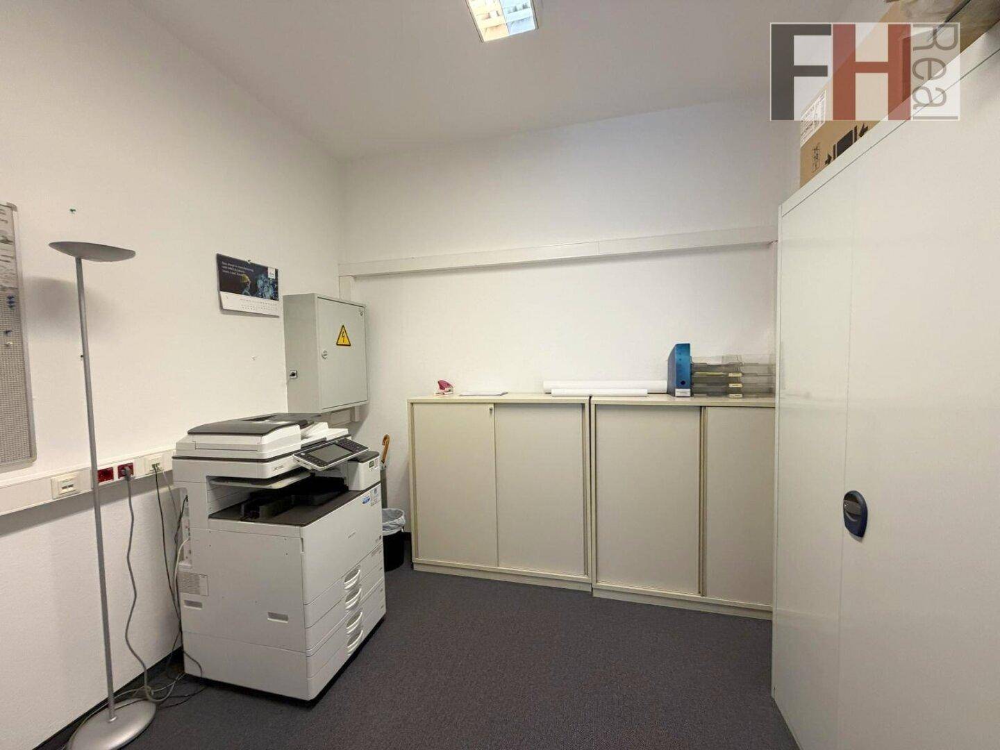 Funktionaler Büroraum mit Kopierer, Aktenschränken und Teppichboden für den täglichen Betrieb.