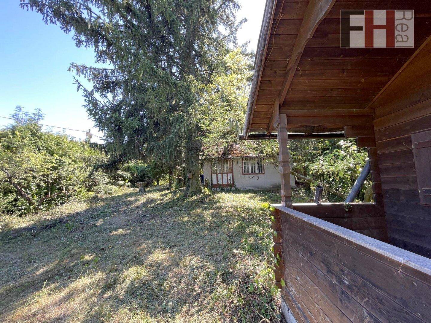 Blick vom Holzschuppen über den naturbelassenen Garten zum charmanten Wohnhaus im Hintergrund.