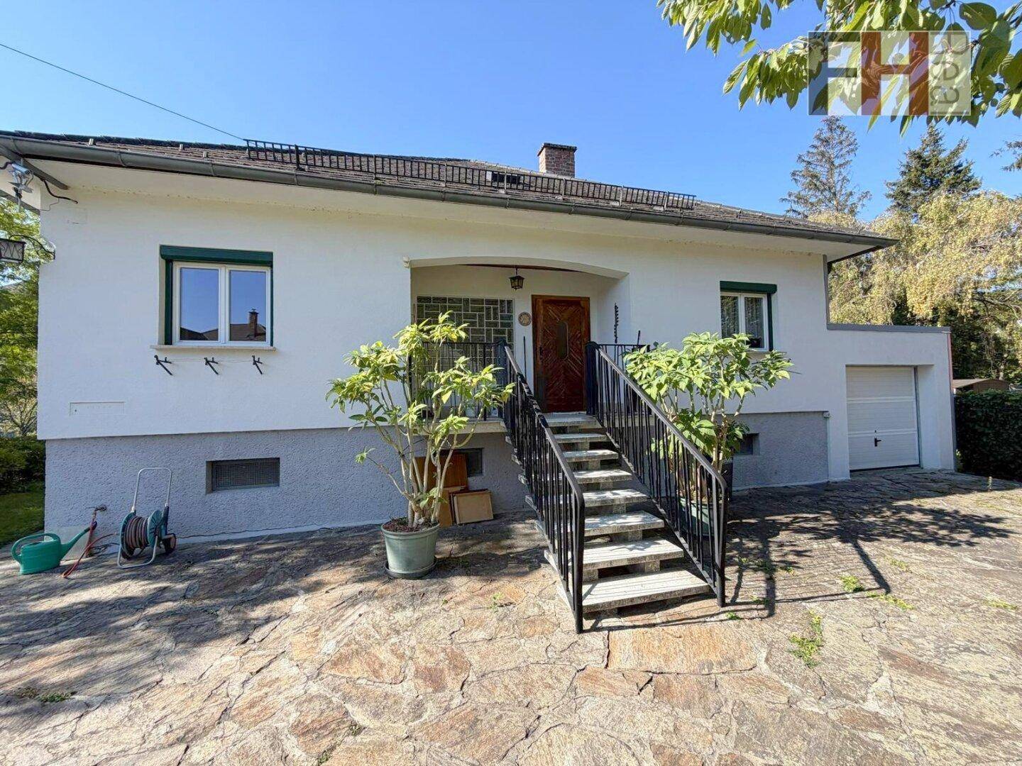 Vorderansicht des Hauses mit Außentreppe zum Eingang und integrierter Garage.