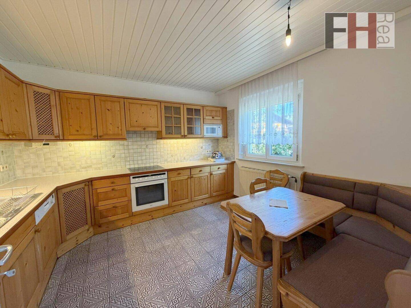 Traditionelle Wohnküche mit Holzschränken, Essbereich und Fliesenboden.