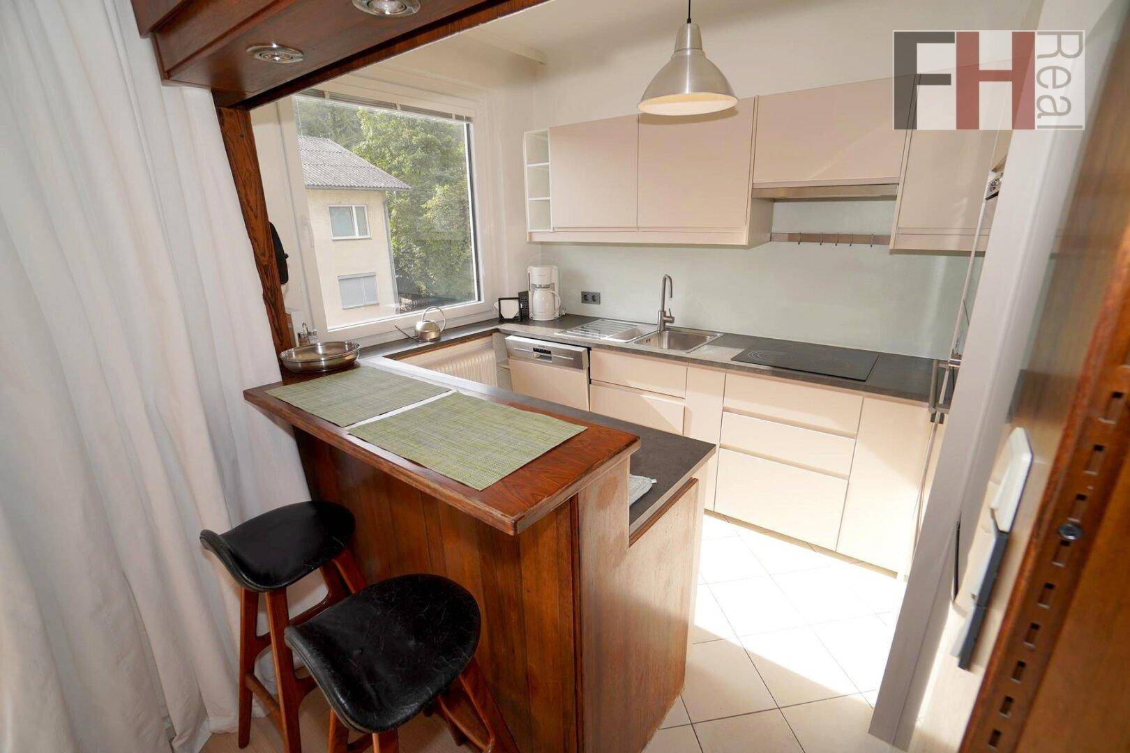Funktionale Küche mit Frühstücksbar, modernen Schränken und Fenster mit Ausblick.