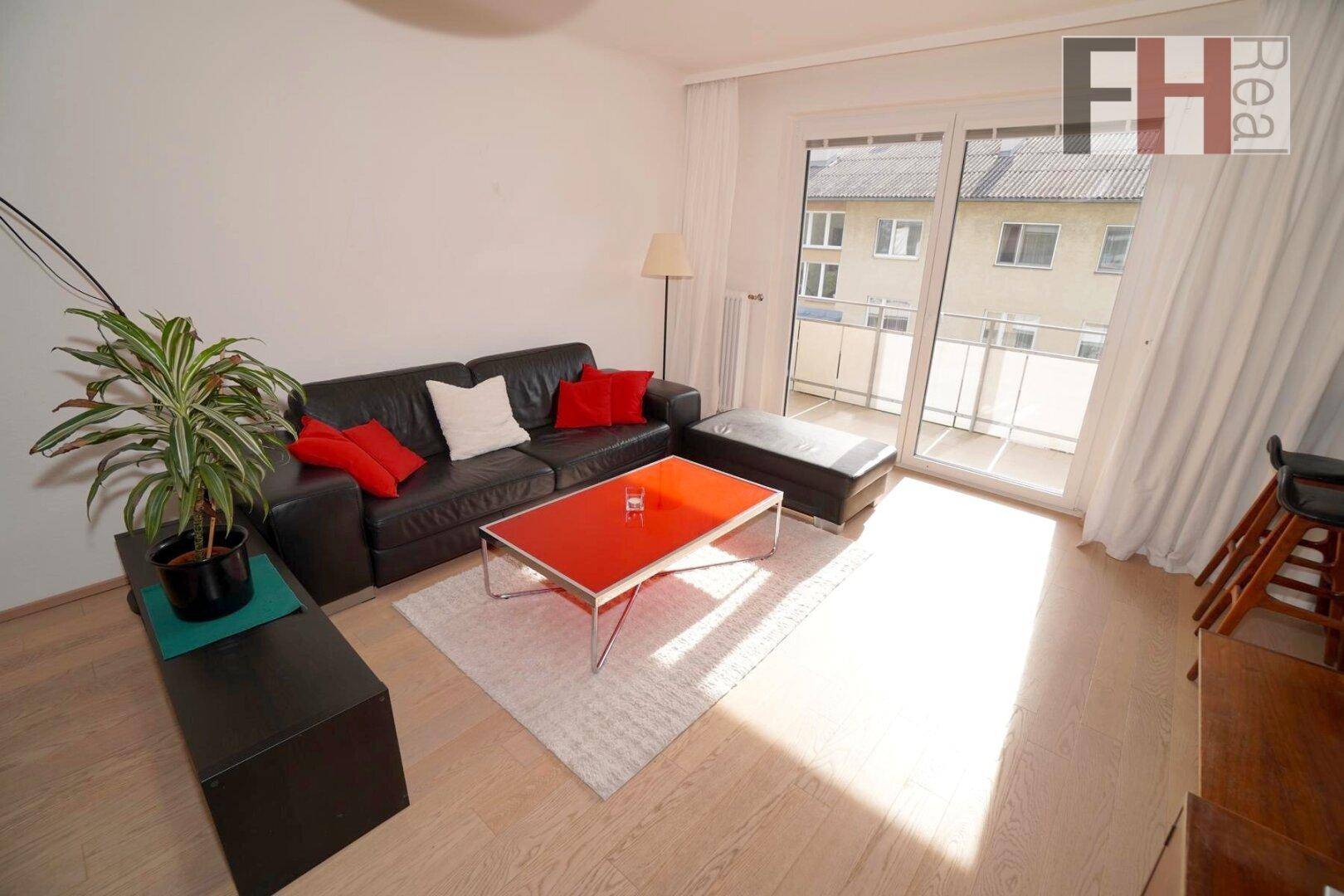 Gemütliches Wohnzimmer mit Sofa, Couchtisch und direktem Zugang zum Balkon.