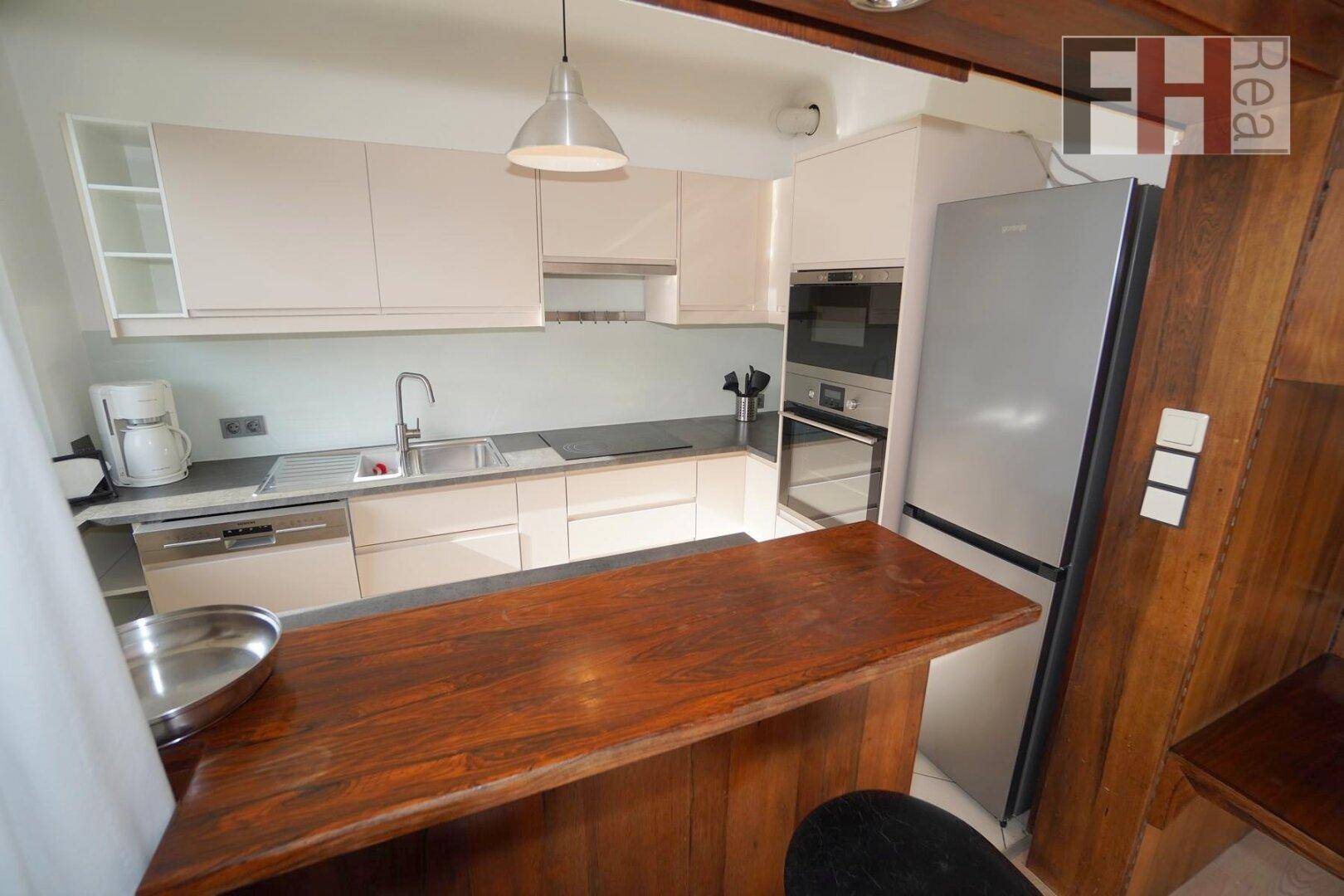 Helle Einbauküche mit integrierten Geräten, Kühlschrank und praktischer Frühstückstheke.