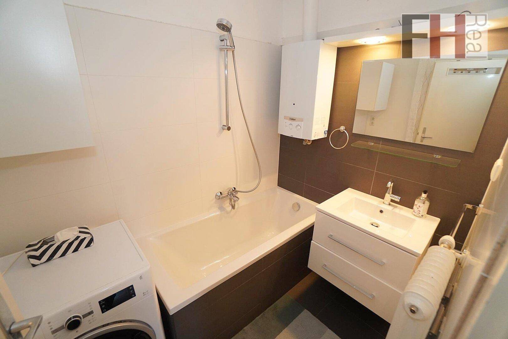 Modernes Badezimmer mit Badewanne, Dusche, Waschbecken und Waschmaschine.