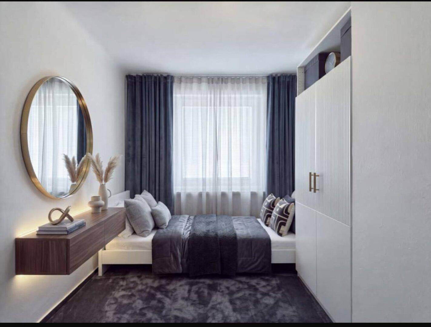 Kompaktes Schlafzimmer mit modernem Design, schwebendem Regal, rundem Spiegel und Einbauschrank.