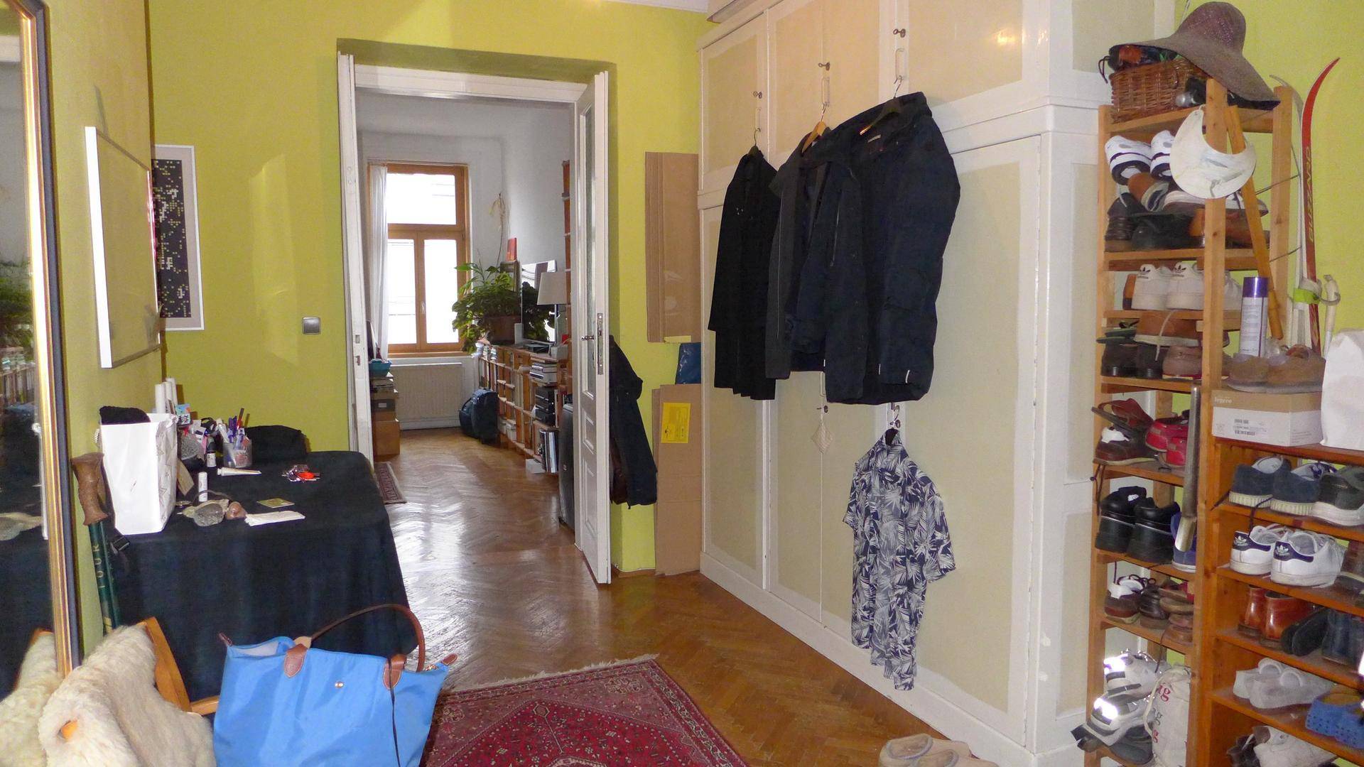 Heller Flur mit Einbauschränken, Parkettboden und Blick in angrenzendes Zimmer.
