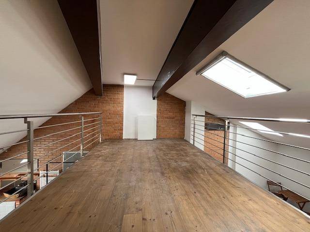 Offene Galerie im Obergeschoss mit Holzboden, Sichtmauerwerk und Dachfenster.