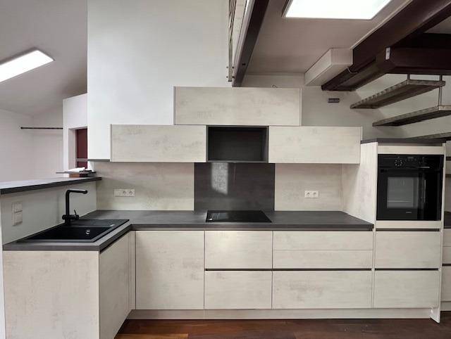 Moderne Einbauküche mit hellen Fronten, Induktionskochfeld und integriertem Backofen.