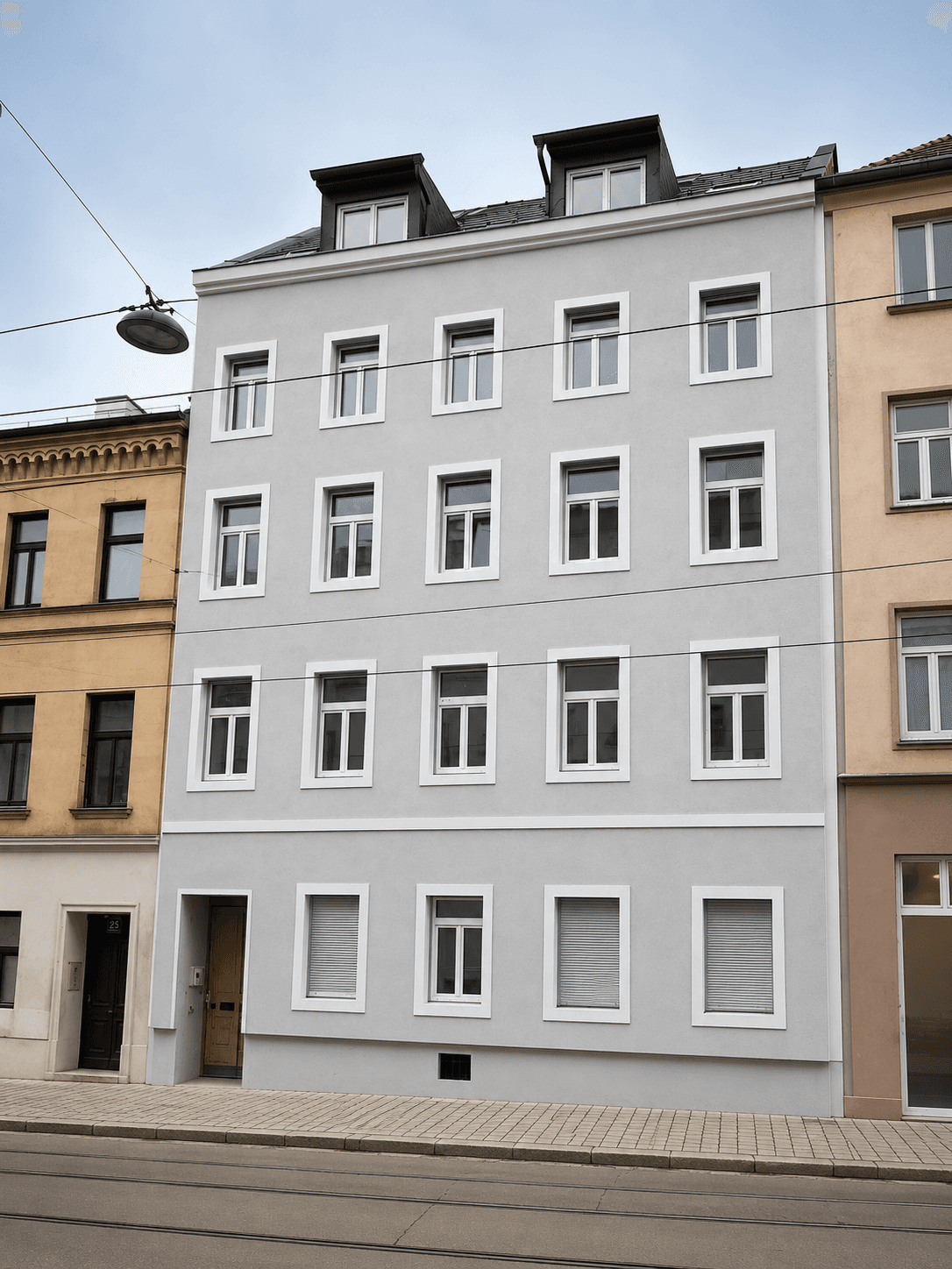 Historisches Mehrfamilienhaus mit frisch gestrichener hellgrauer Fassade und vielen Fenstern.