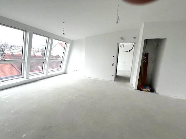 Unfertiger Innenraum mit großen Dachfenstern, der viel natürliches Licht hereinlässt.