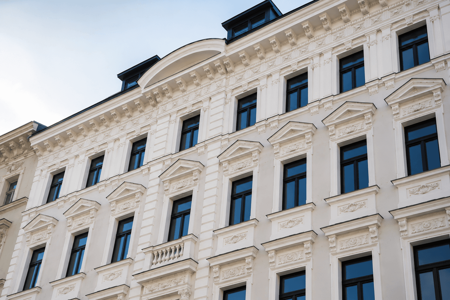 Eine elegante historische Fassade mit reich verzierten Fenstern und einem französischen Balkon.