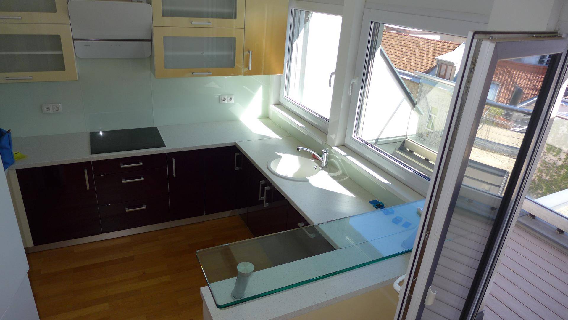 Helle Küche mit modernen Schränken, Induktionskochfeld und einer eleganten Glas-Frühstücksbar.