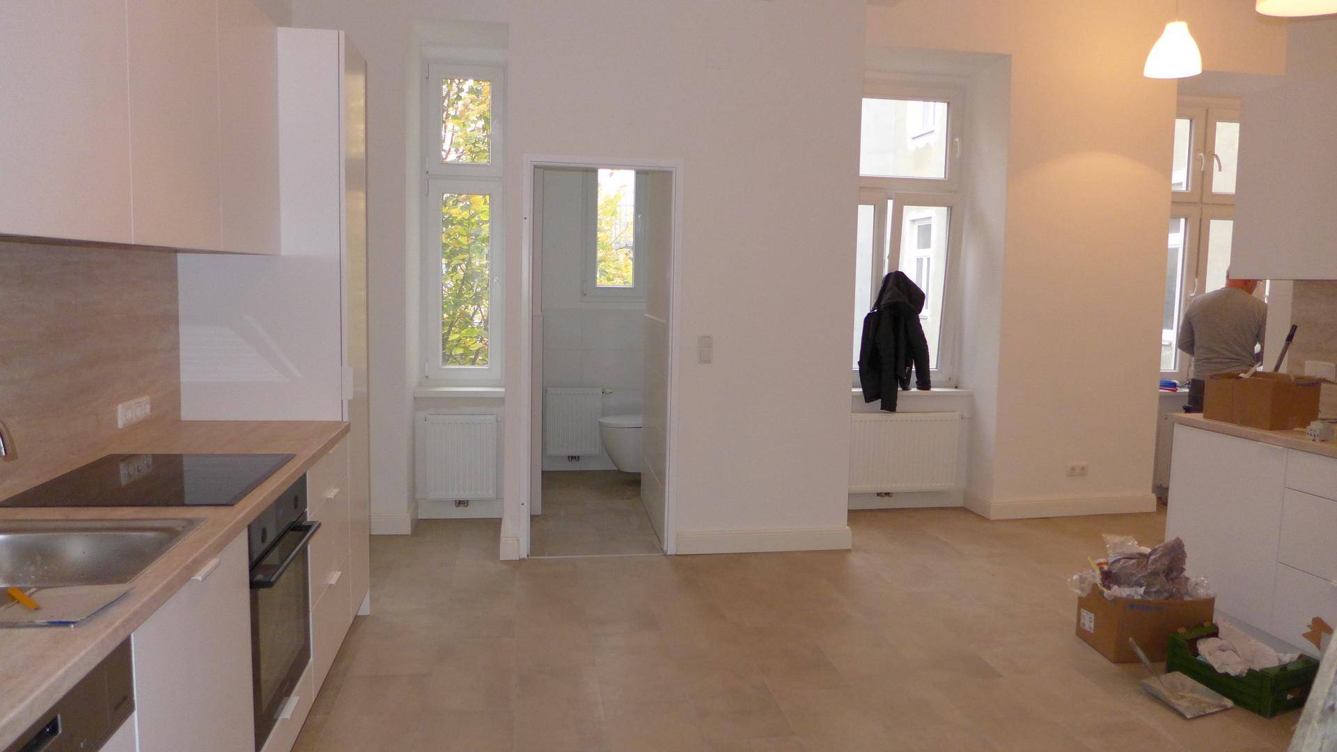 Offener Küchenbereich mit modernen Einbauten und Blick in ein angrenzendes Badezimmer mit Fenster.