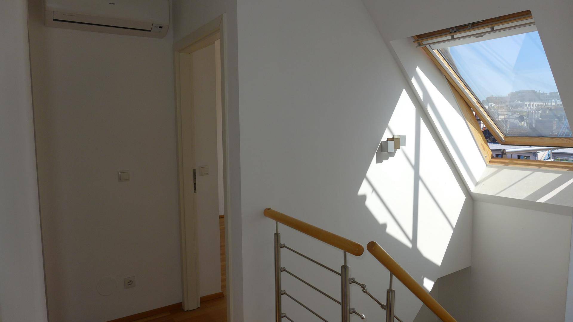 Heller Treppenaufgang mit Dachfenster, das viel Sonnenlicht hereinlässt.