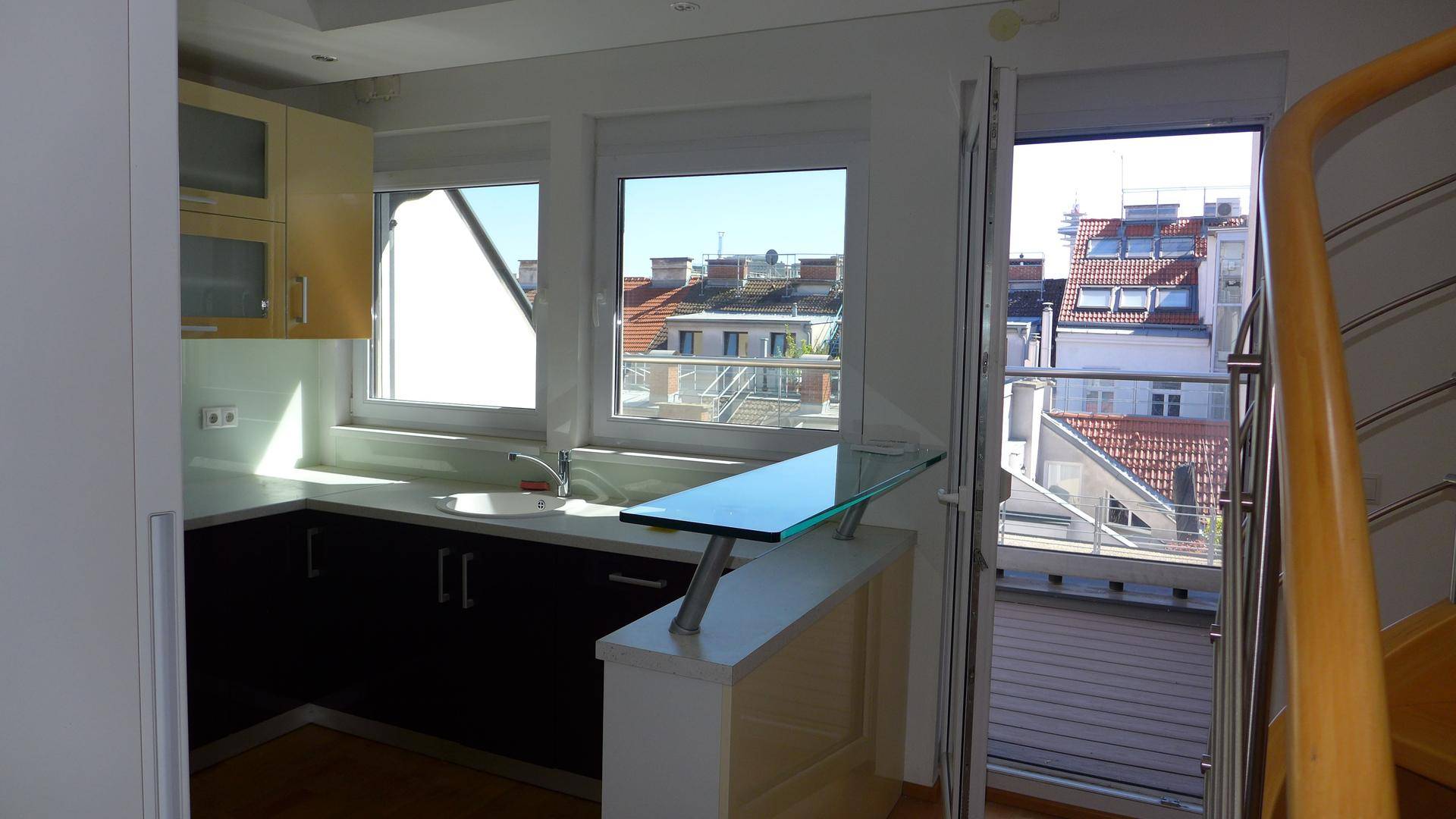 Moderne Küche mit Kochinsel, Blick auf die Dächer und Zugang zur Terrasse.