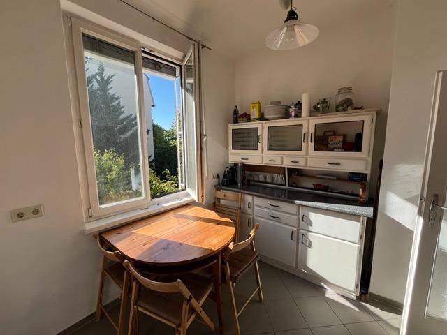 Gemütliche Küche mit Esstisch am Fenster, traditionellen Schränken und viel Tageslicht.