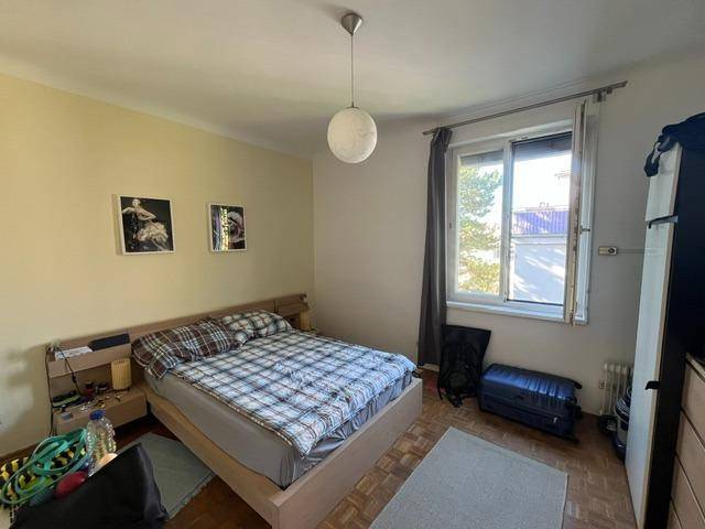 Schlafzimmer mit Doppelbett, Fenster und Holzboden, hell und funktional eingerichtet.