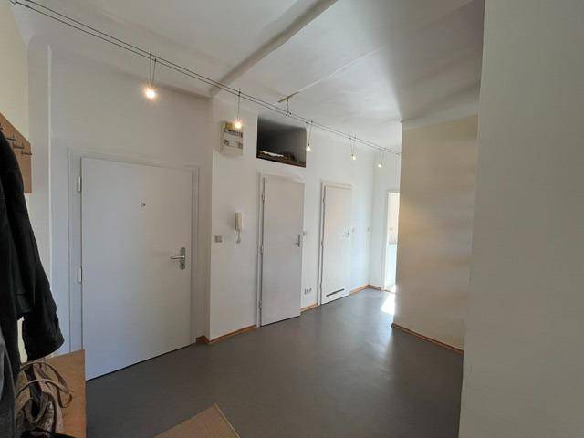Heller Flur mit mehreren weißen Türen und einfacher Beleuchtung an der Decke.