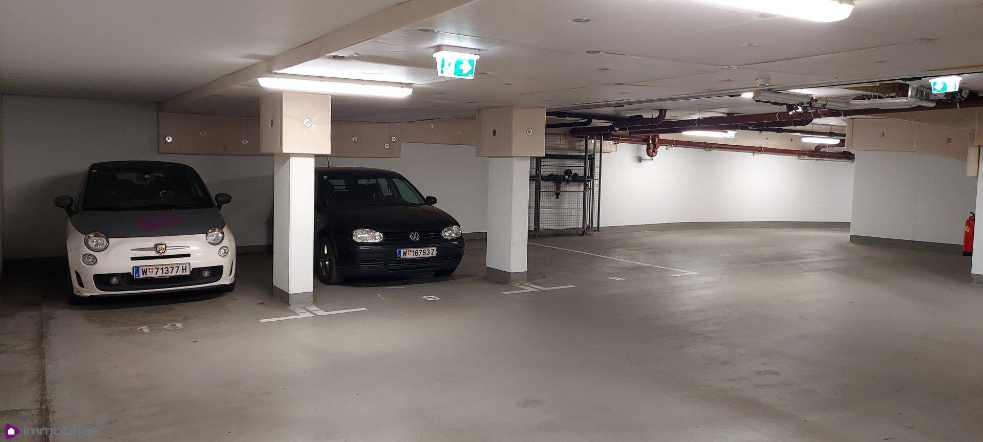 Geräumige Tiefgarage mit mehreren geparkten Autos und guter Beleuchtung.