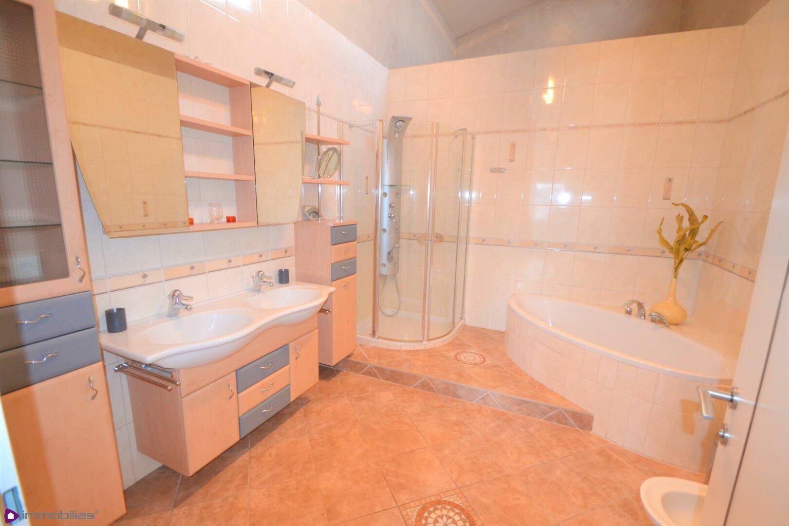 Geräumiges Badezimmer mit Doppelwaschbecken, Eckbadewanne und separater Duschkabine.