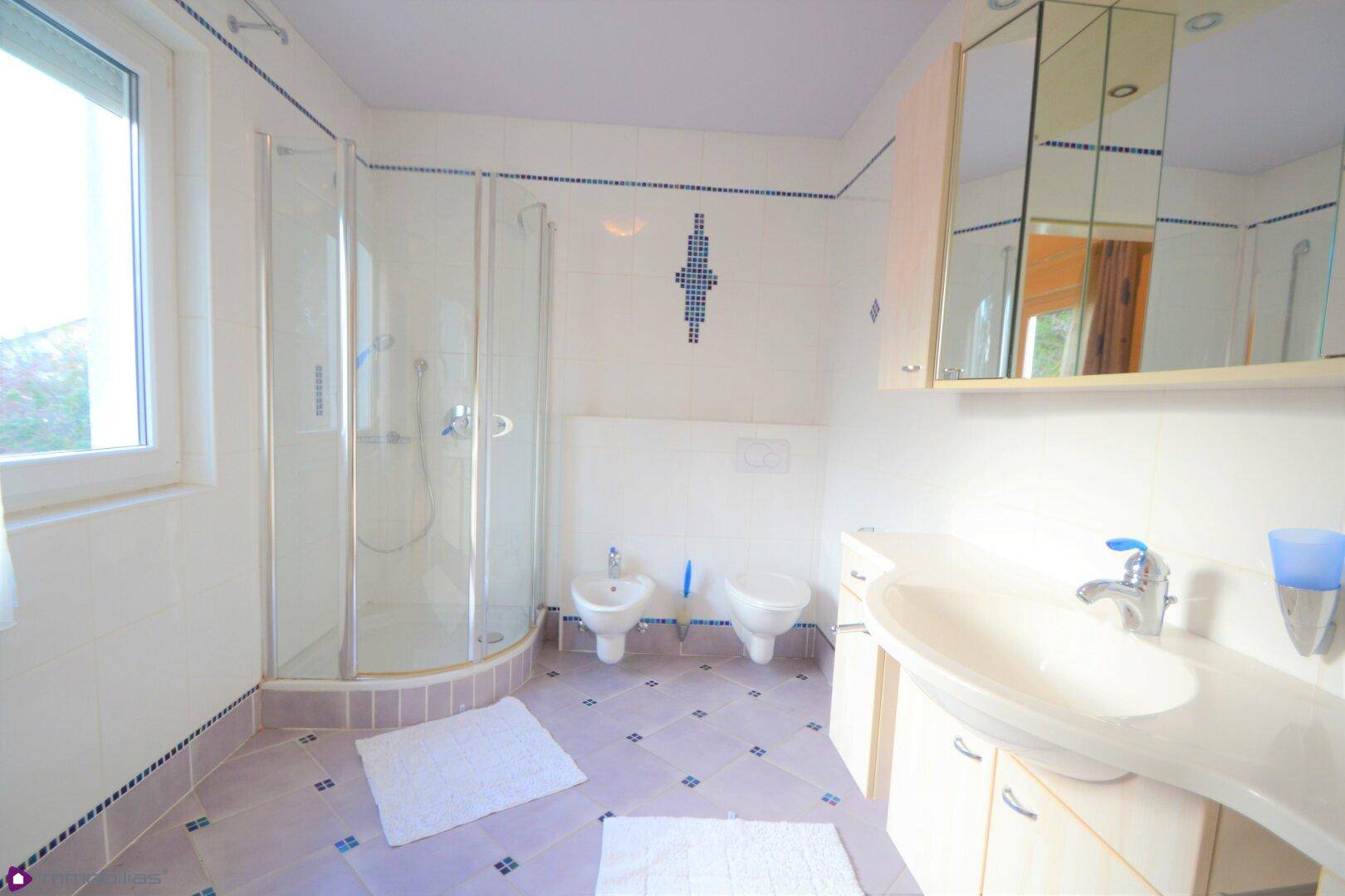 Helles Badezimmer mit Dusche, WC, Bidet und Fenster für natürliche Belüftung.