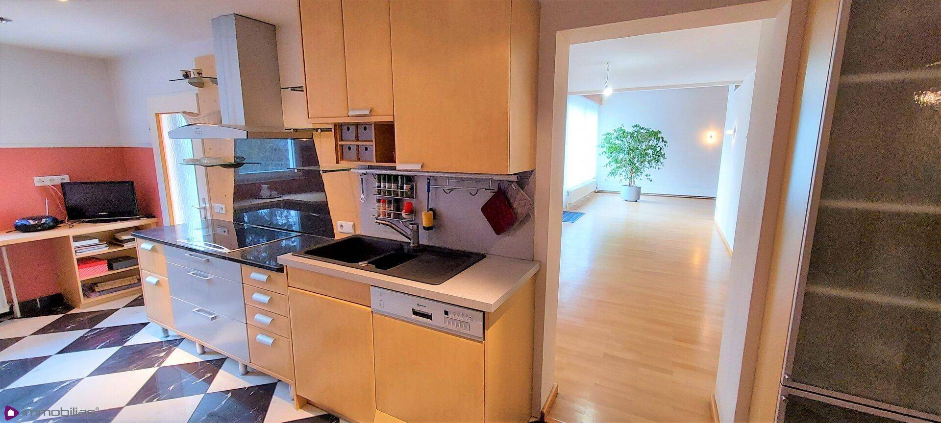 Funktionale Küche mit Holzschränken, modernen Geräten und direktem Zugang zum Wohnbereich.