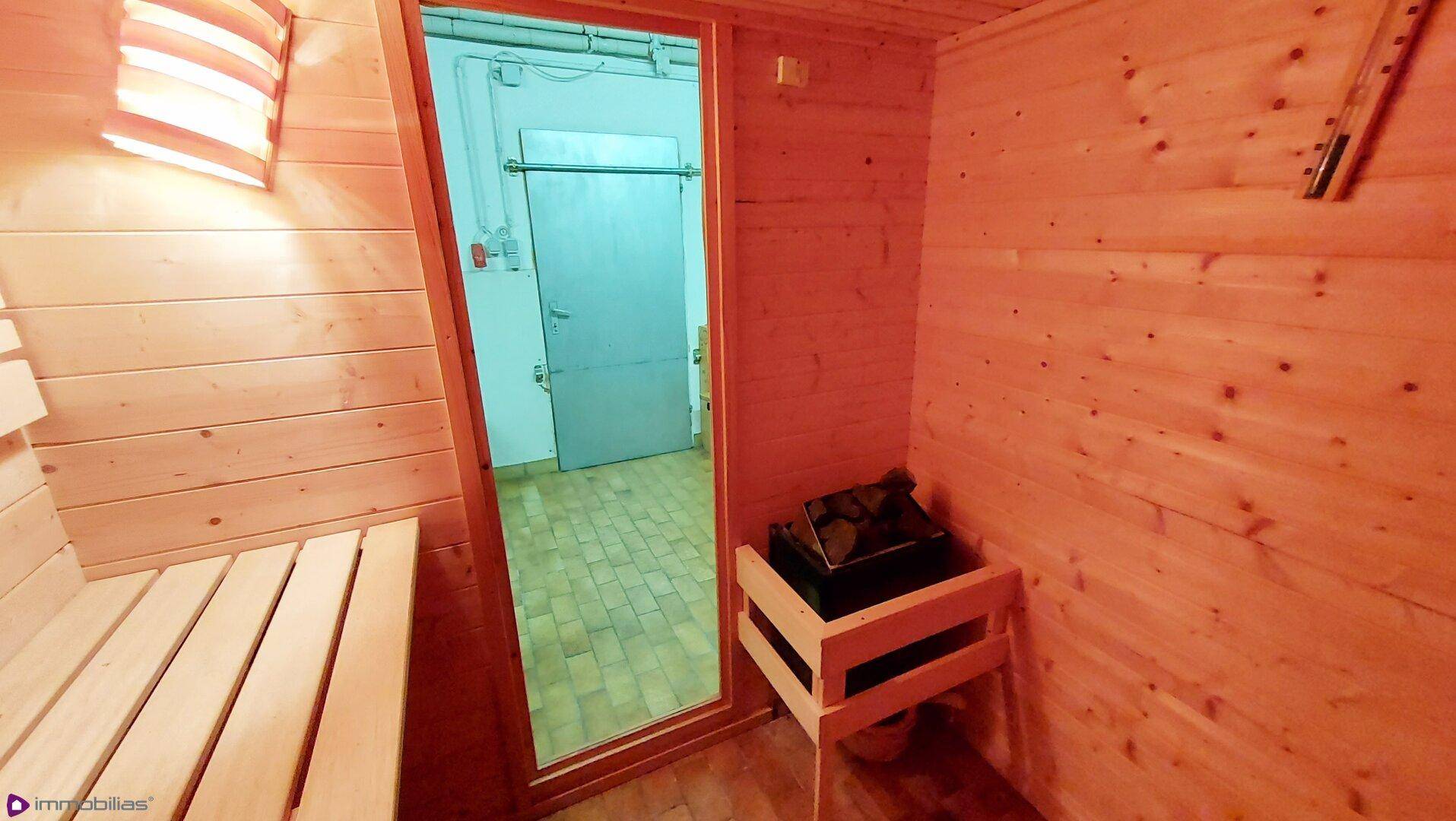 Innenansicht einer Sauna mit Heizofen und Holzbänken, bereit zur Nutzung.