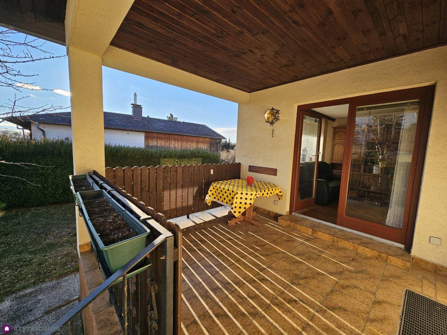 Überdachte Terrasse mit Fliesenboden und Blick auf die umliegende Landschaft.