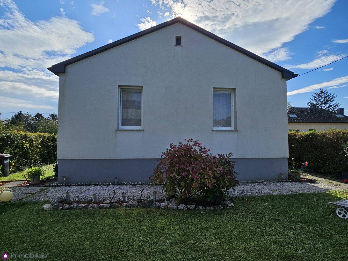 Rückansicht eines Einfamilienhauses mit schlichter Fassade und kleinem Vorgartenbereich.