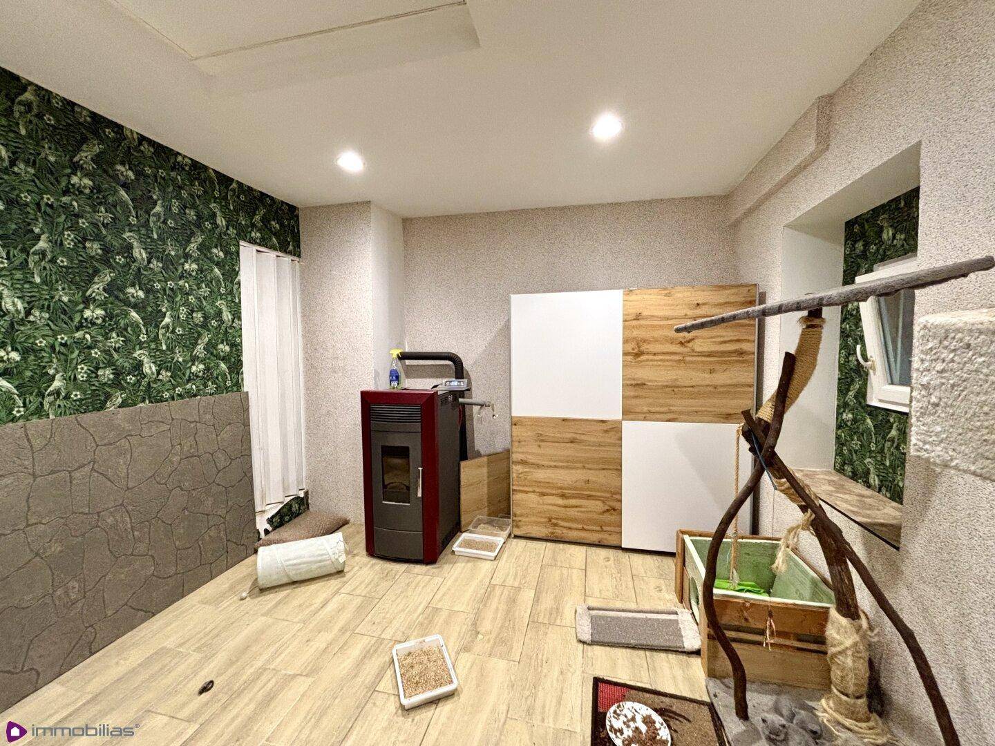 Raum mit Fliesenboden, grüner Tapete und einem modernen Pelletofen.