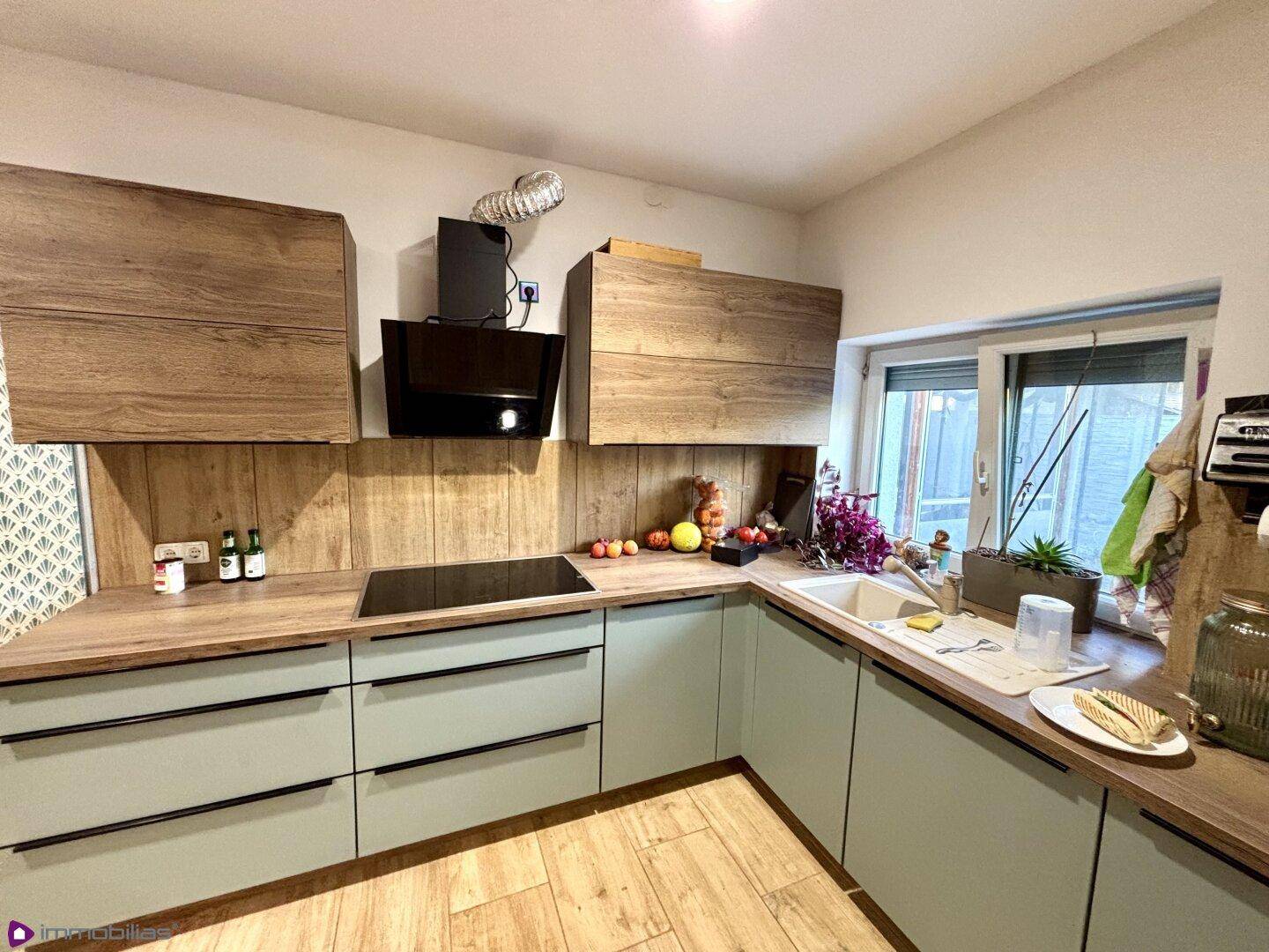 Helle Küche mit modernen Holzfronten, mintgrünen Unterschränken und Induktionskochfeld.