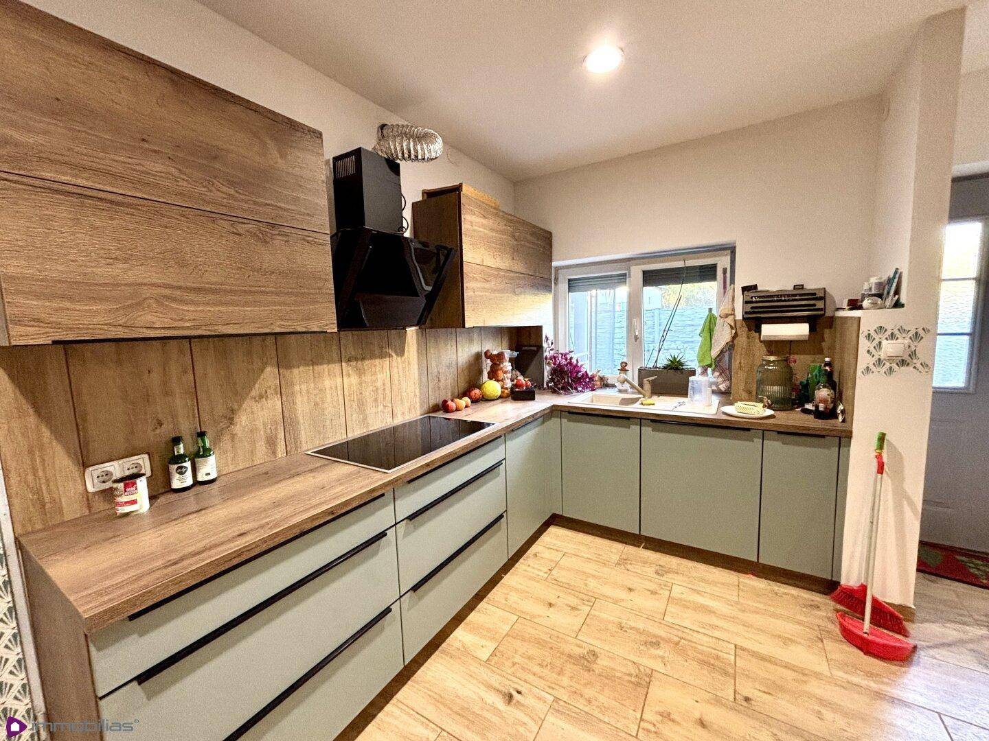 Moderne Küche mit Holz- und mintgrünen Schränken, Induktionskochfeld und Fenster.