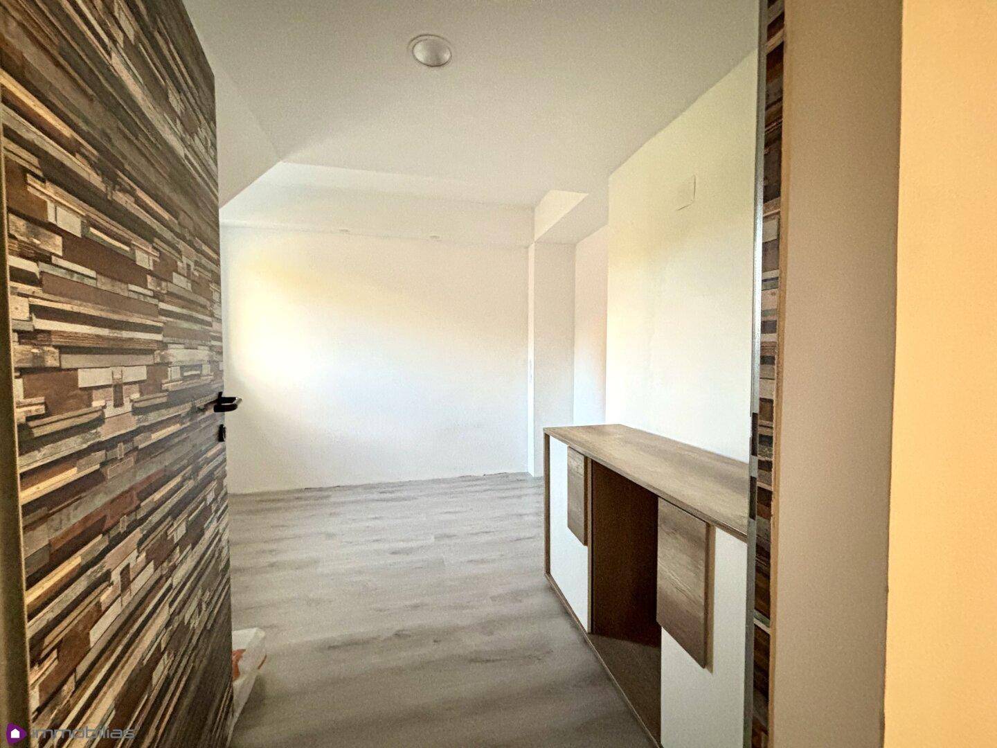 Leerer Raum mit hellem Laminatboden und einem kleinen Schrank.