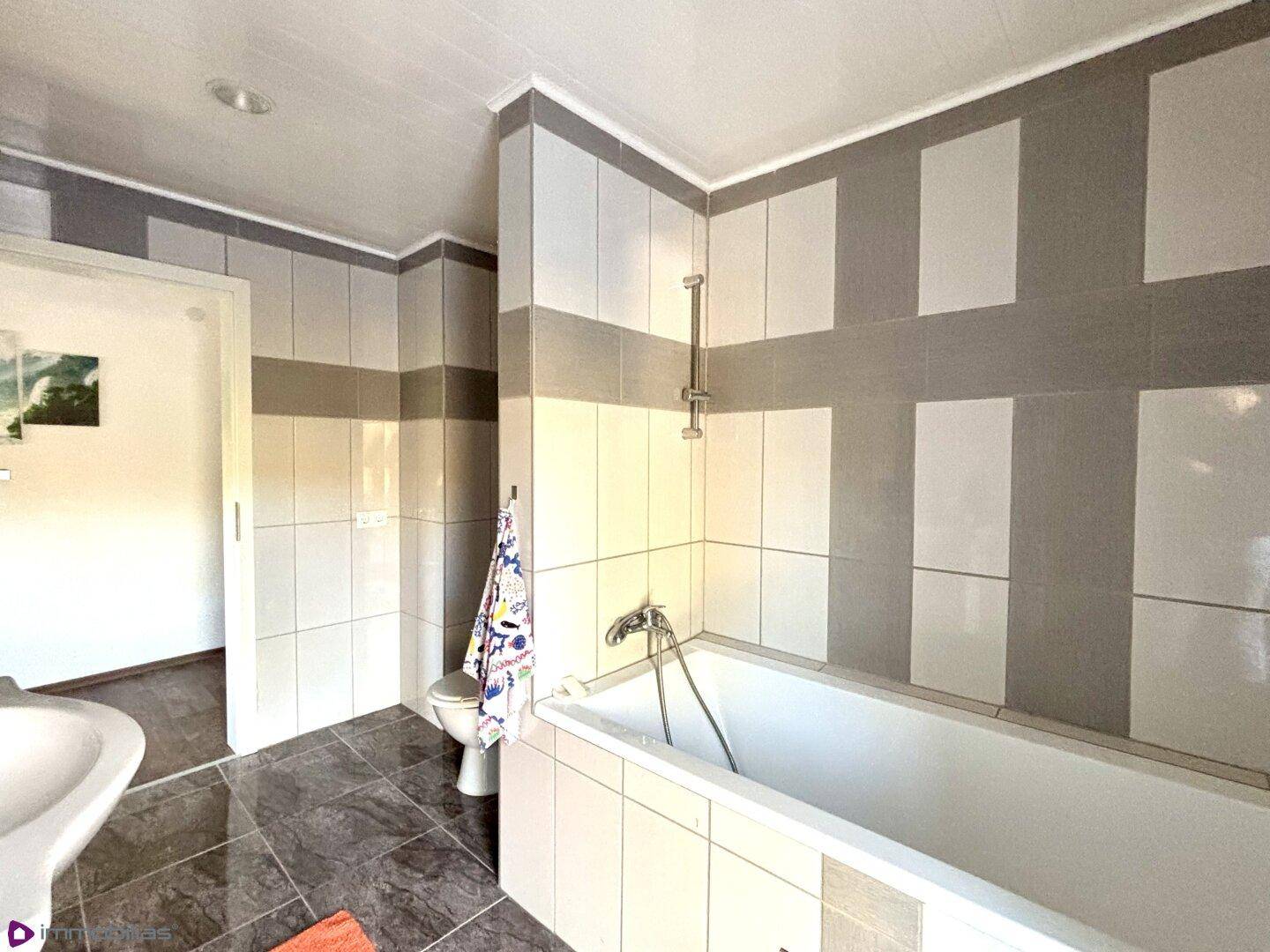 Geräumiges Badezimmer mit Badewanne, Dusche und modernen Fliesen.