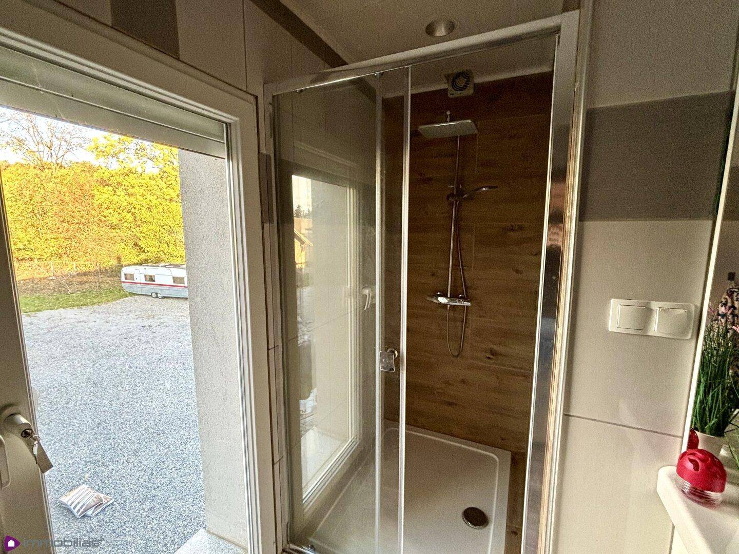 Duschkabine im Badezimmer mit Blick nach draußen und Holzwand.