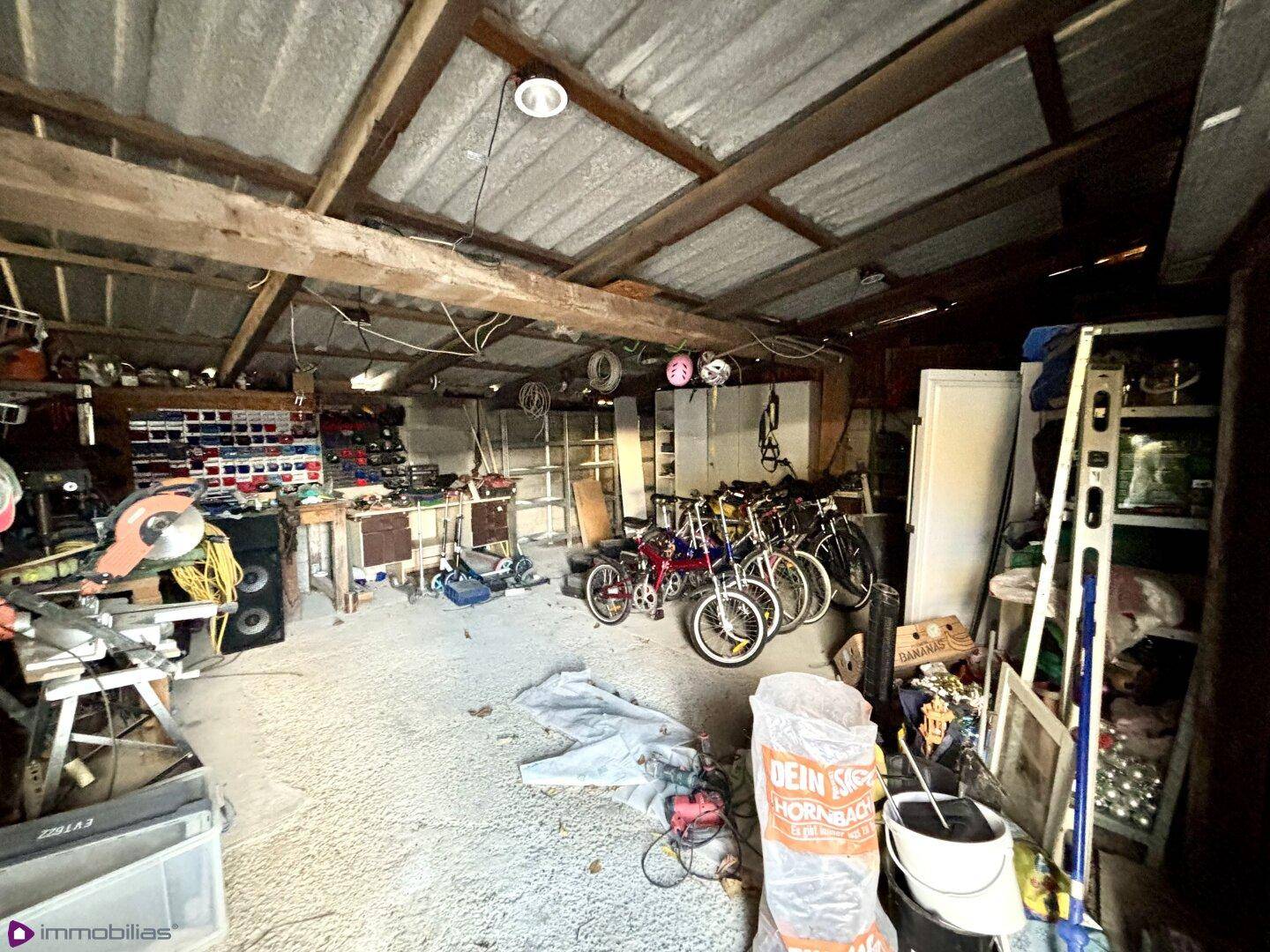 Geräumiger Werkstattbereich mit Werkzeugen, Fahrrädern und sichtbaren Holzbalken.