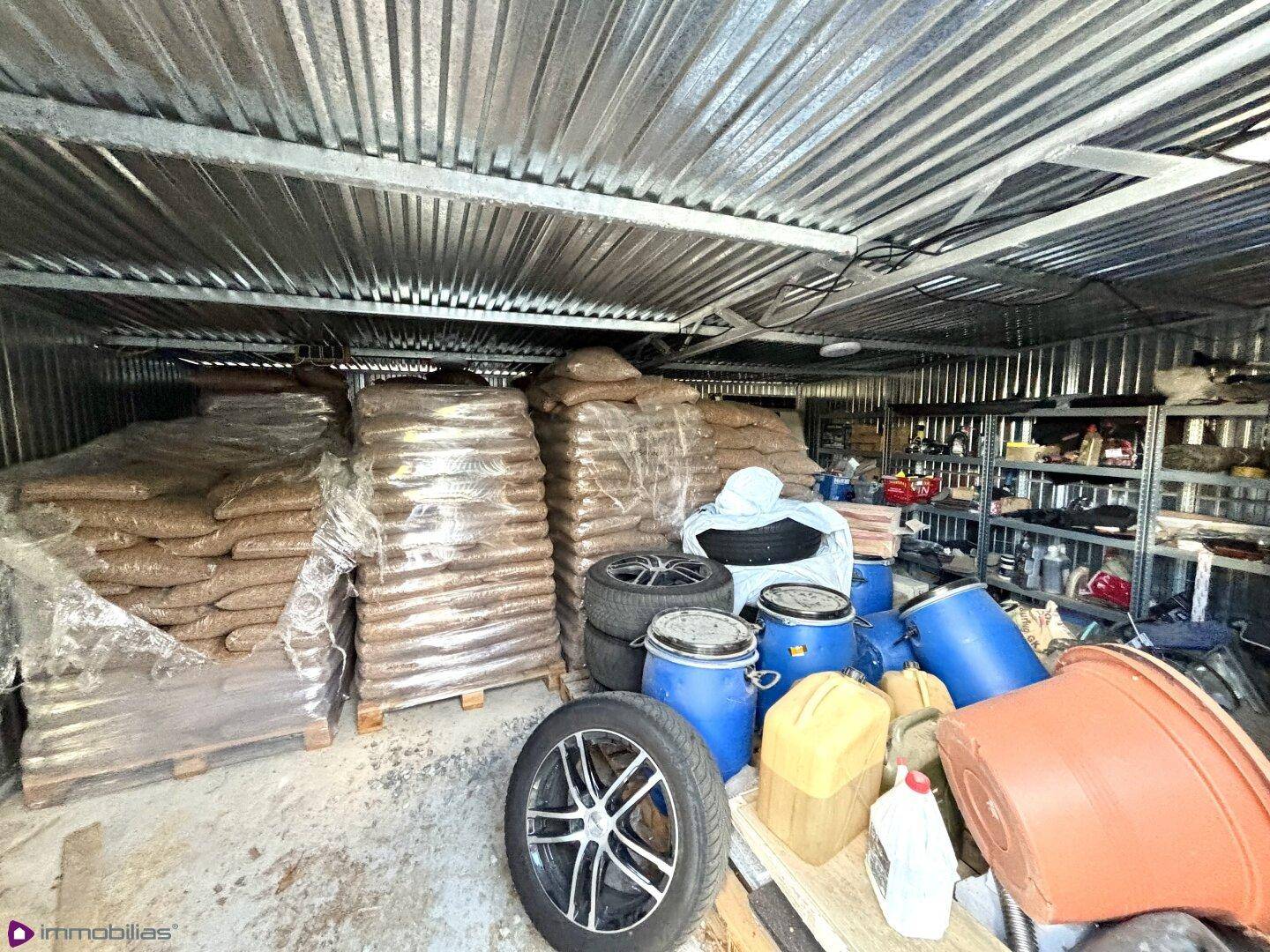 Lagerraum mit gestapelten Säcken, Reifen und Wellblechwänden.