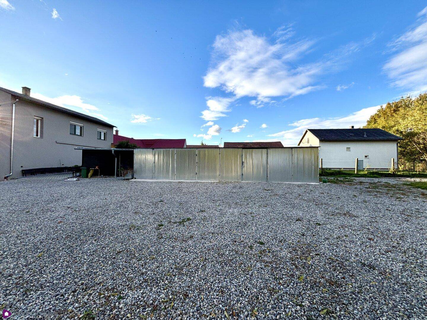 Große Kiesfläche mit Metalllagereinheiten im Hintergrund unter blauem Himmel.