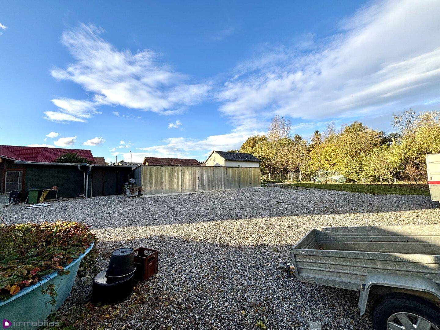 Weitläufige Kiesfläche mit verschiedenen Nebengebäuden unter blauem Himmel.
