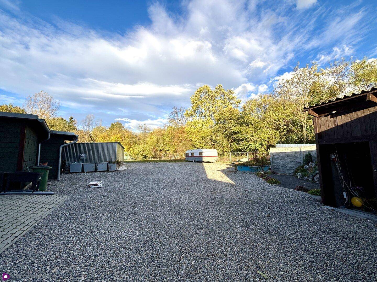 Großer Außenbereich mit Kies, Nebengebäuden und viel Platz.