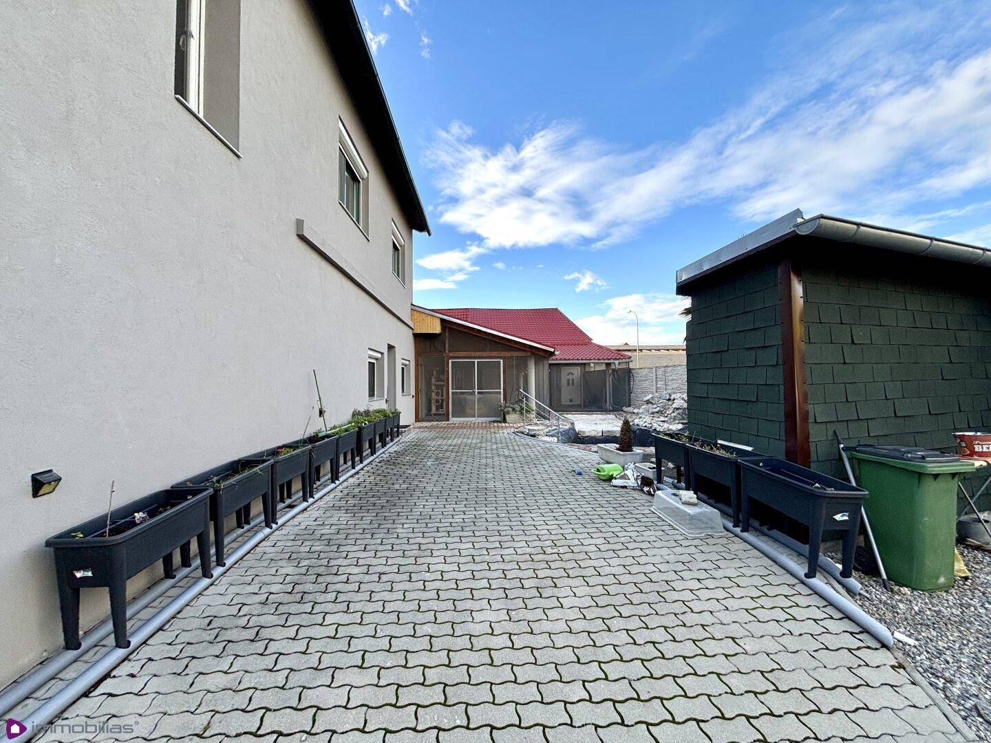 Gepflasterte Einfahrt neben dem Gebäude mit Pflanzkübeln.