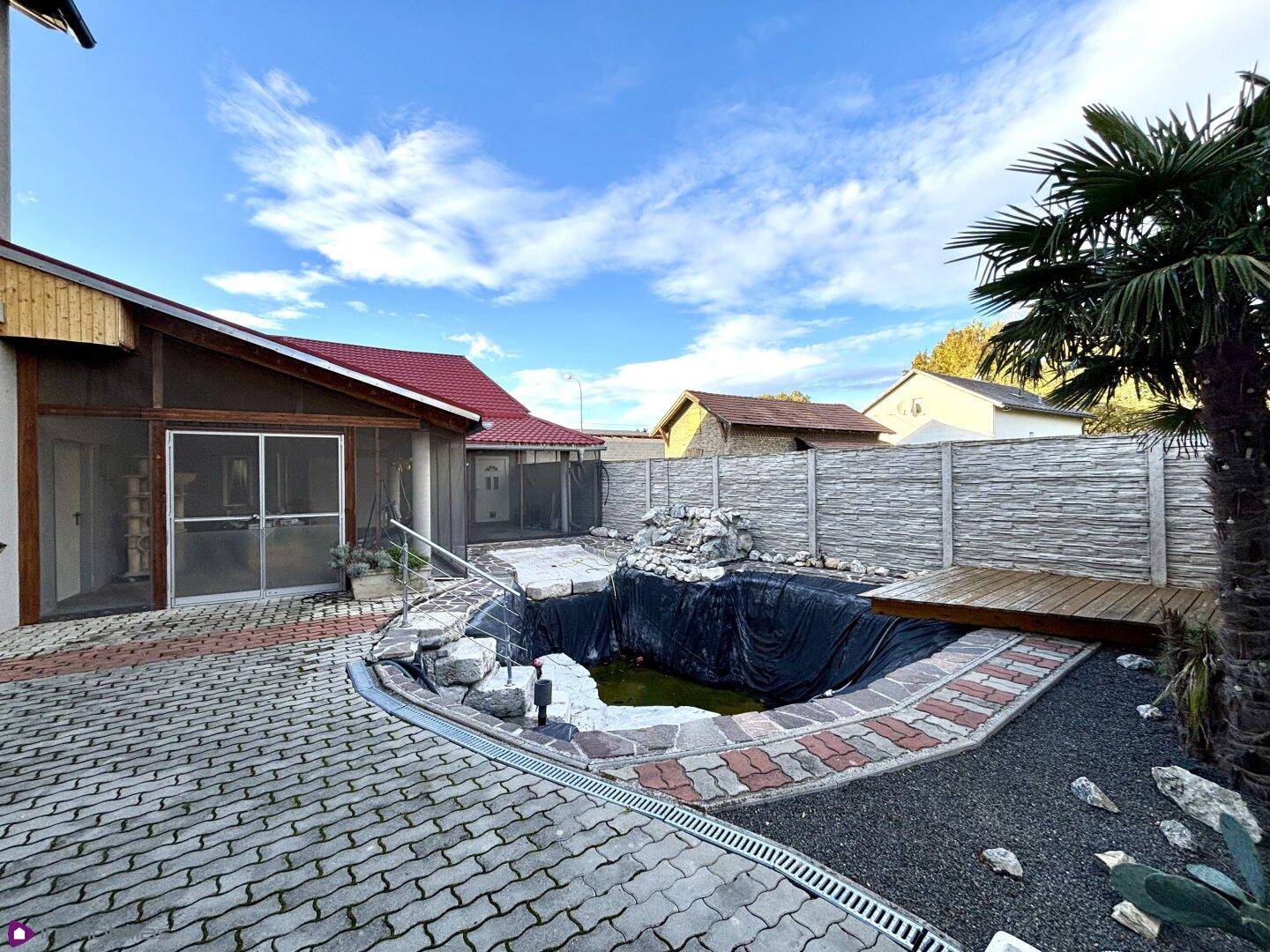 Gartenbereich mit einem Teich, gepflastertem Weg und Palmen.