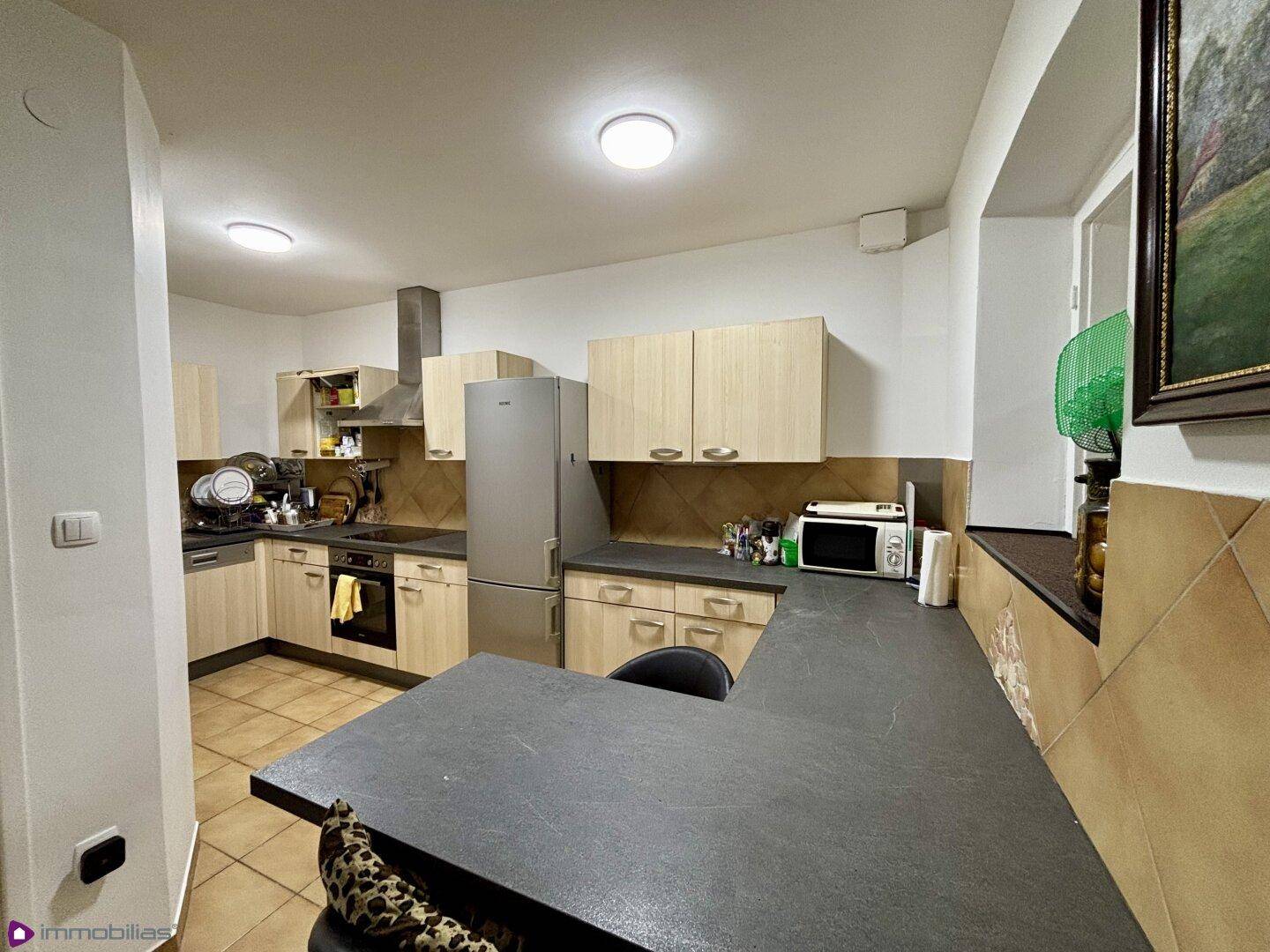 Geräumige Küche mit Frühstücksbar, Einbaugeräten und Fliesenboden.