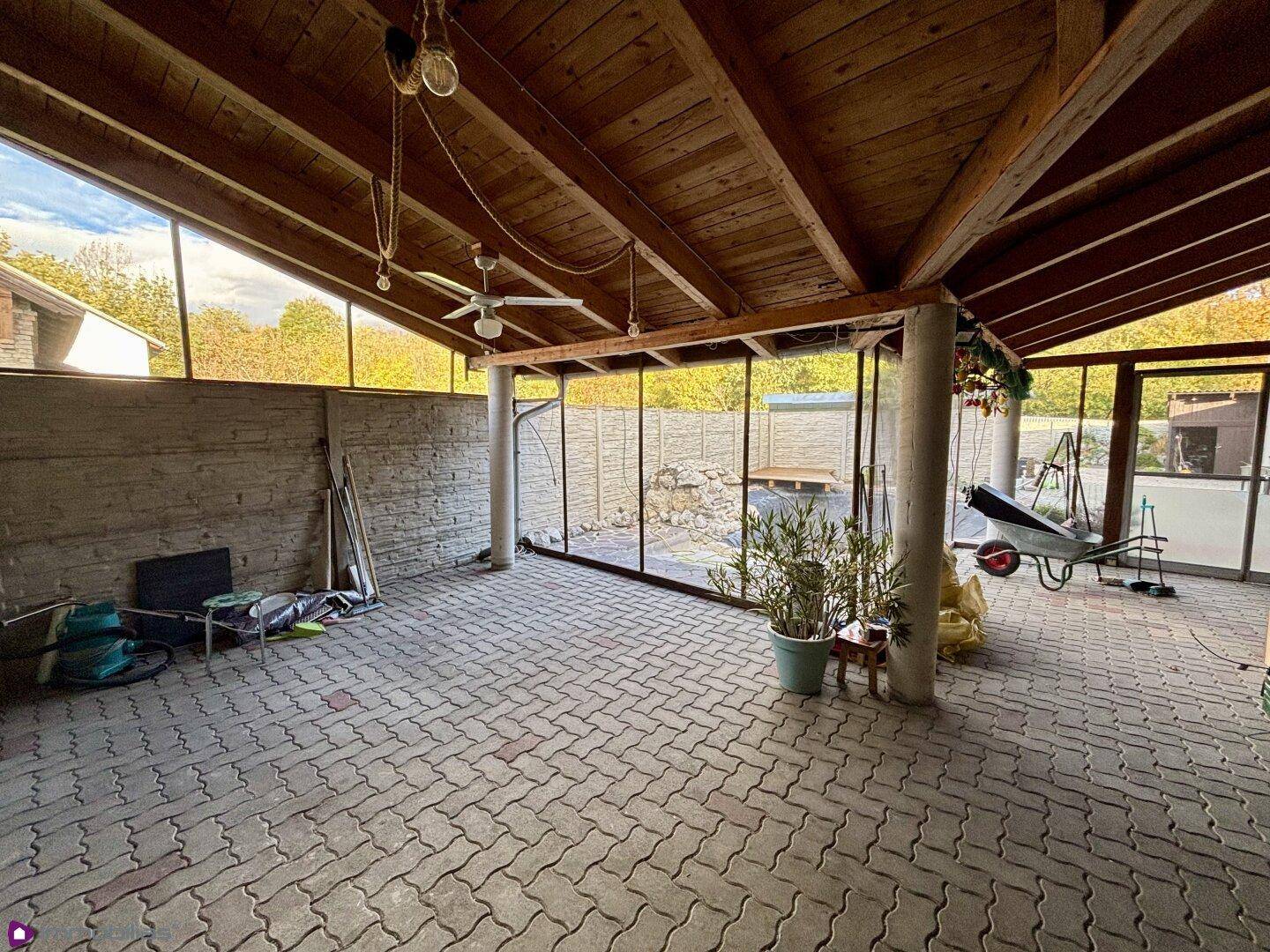 Überdachter Außenbereich mit gepflastertem Boden und Holzdachkonstruktion.