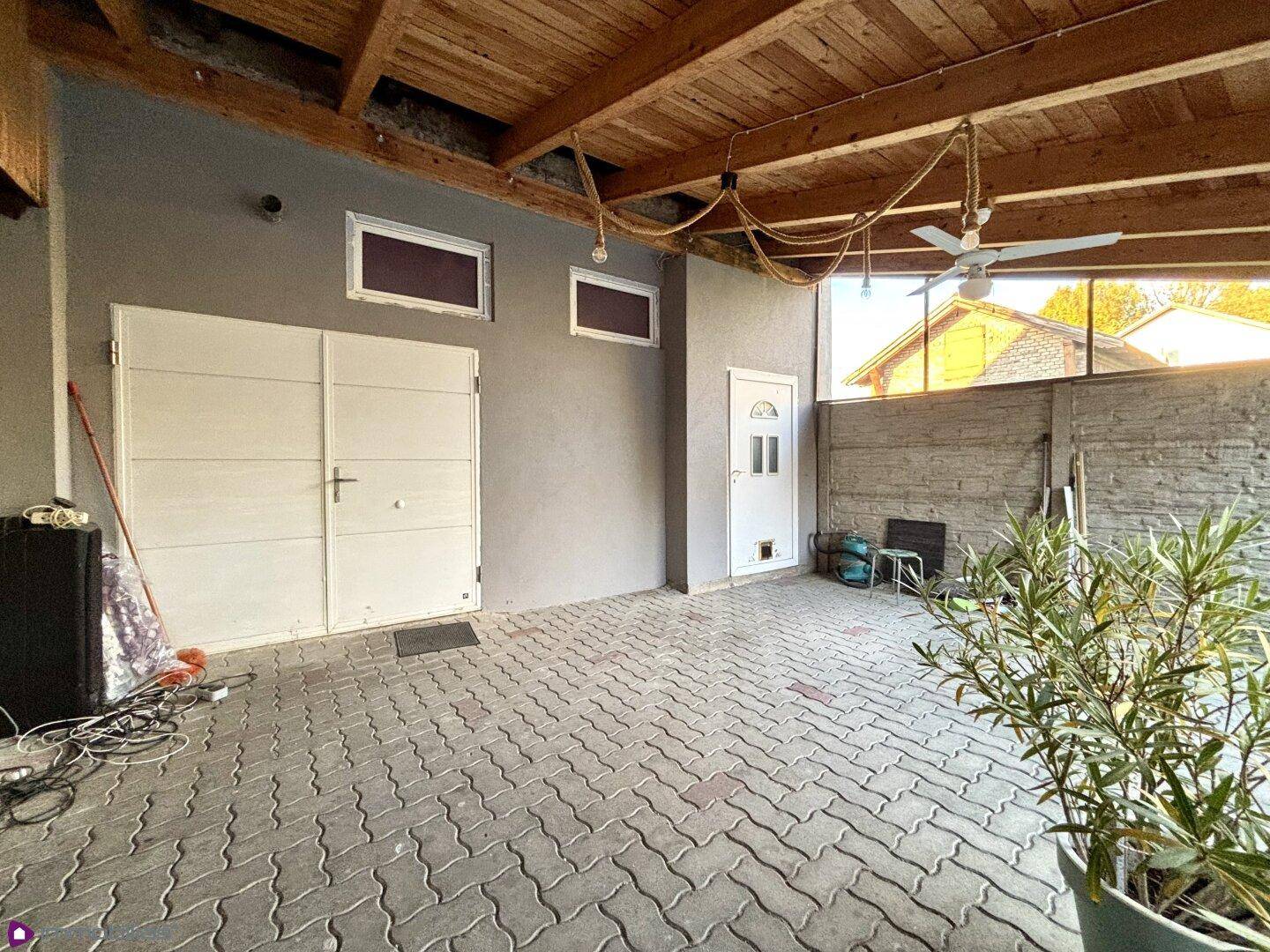 Großer überdachter Außenbereich mit Doppeltür und gepflastertem Boden.