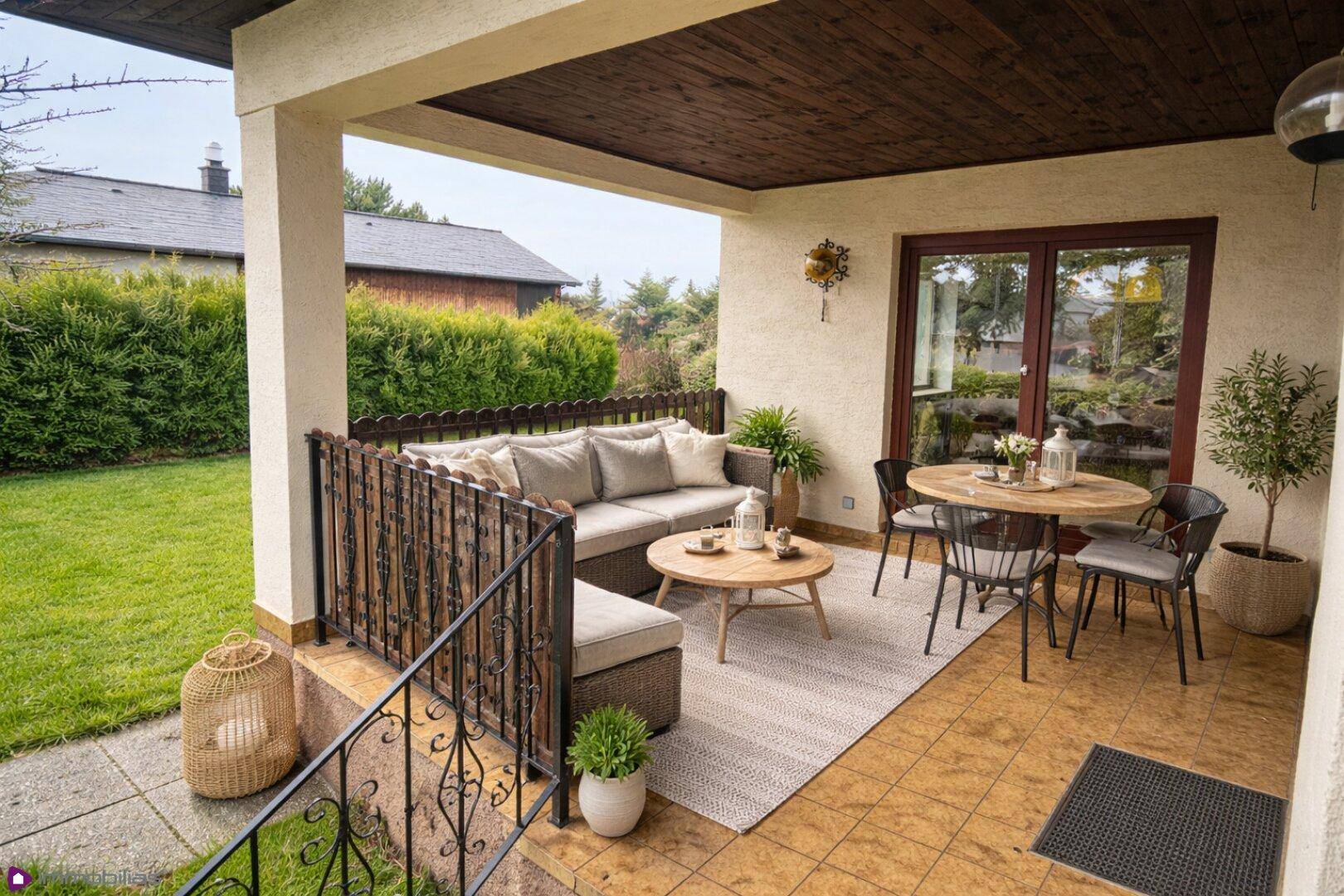 Überdachte Terrasse mit bequemen Gartenmöbeln und Zugang zum grünen Gartenbereich.