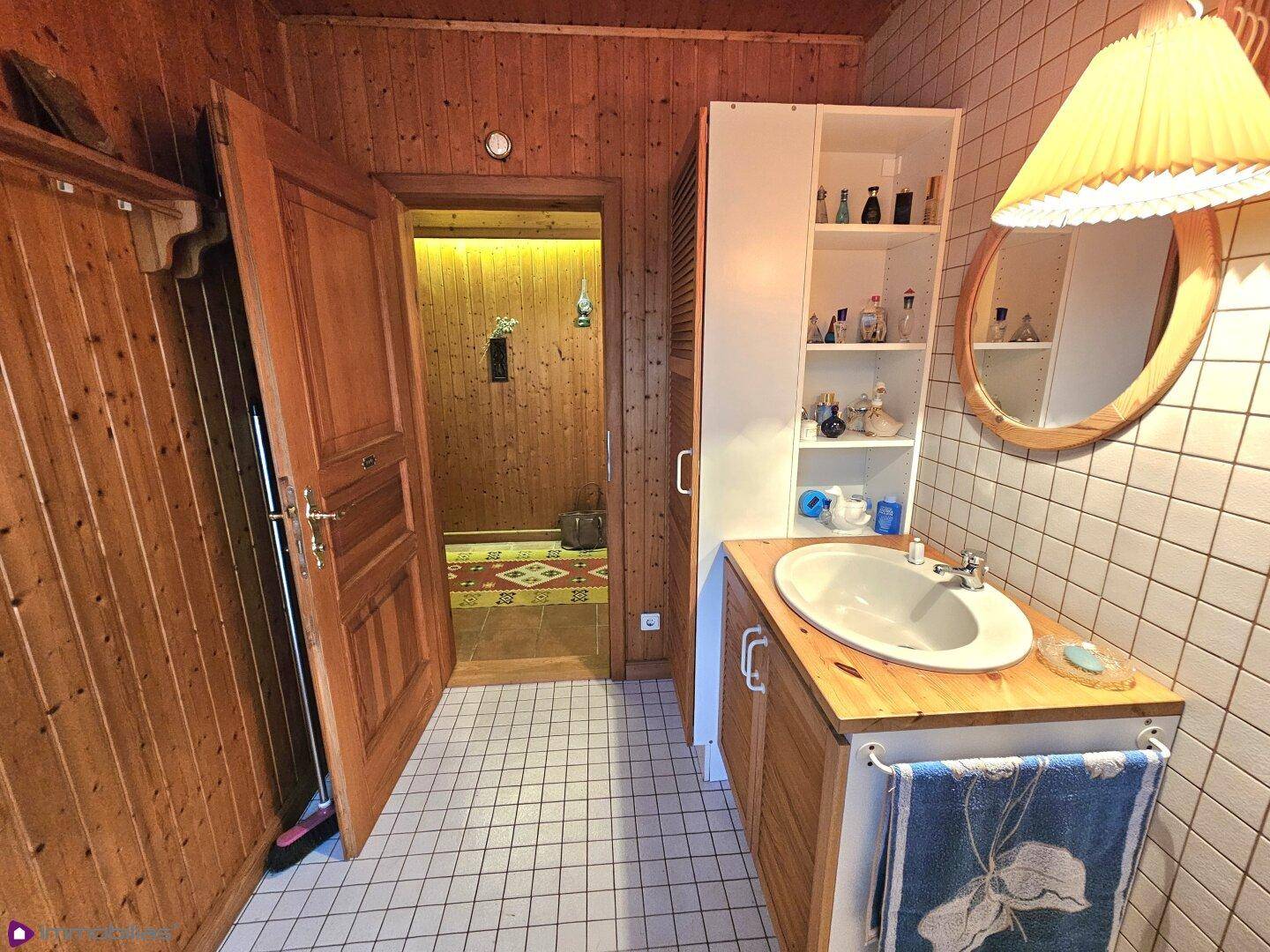 Badezimmer mit Holzvertäfelung, Waschbecken und Fliesenboden, sehr funktional.